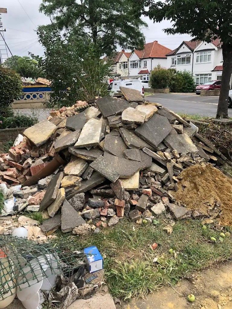 Pile of construction debris and rubble on grassy area in a residential neighborhood.